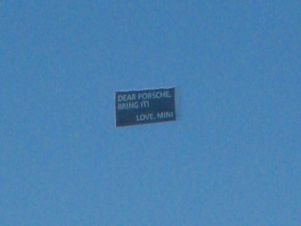 plane flying a banner that reads Dear Porsche, Bring It.  Love, Mini