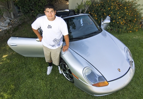 steven ortiz standing next to the porsche boxster he swapped for on craigslist