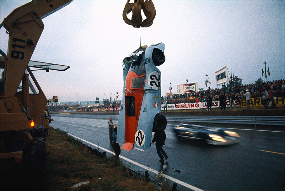 A Porsche 917KH in Gulf Oil Livery is lifted from the race track by a crane